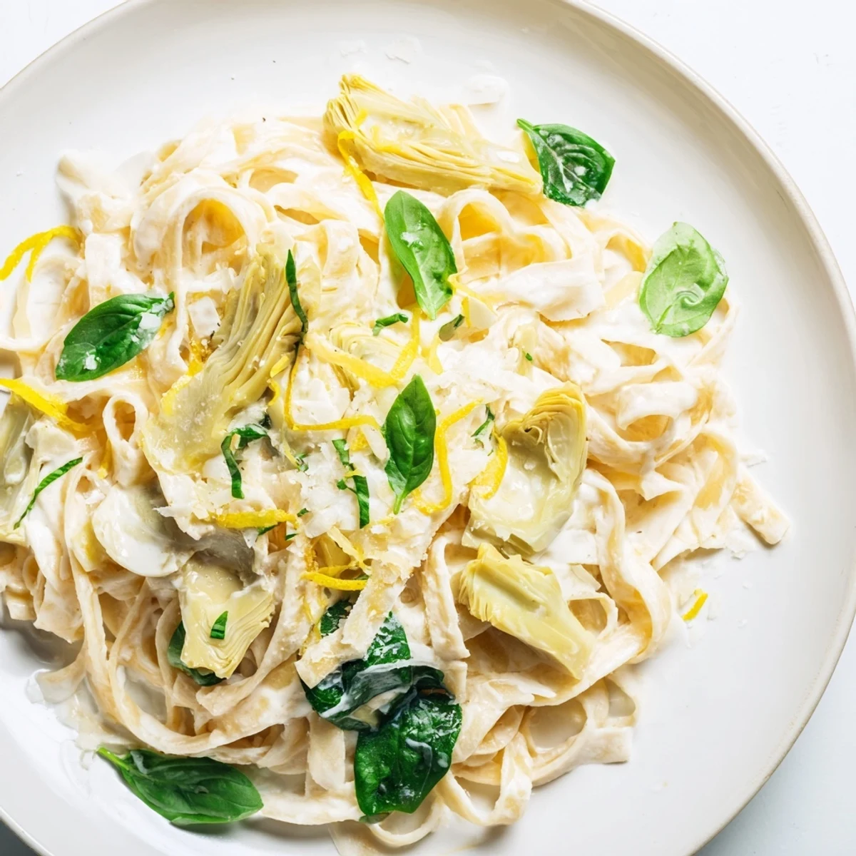 Steaming bowl of creamy lemon artichoke pasta, beautifully garnished, ready to enjoy.