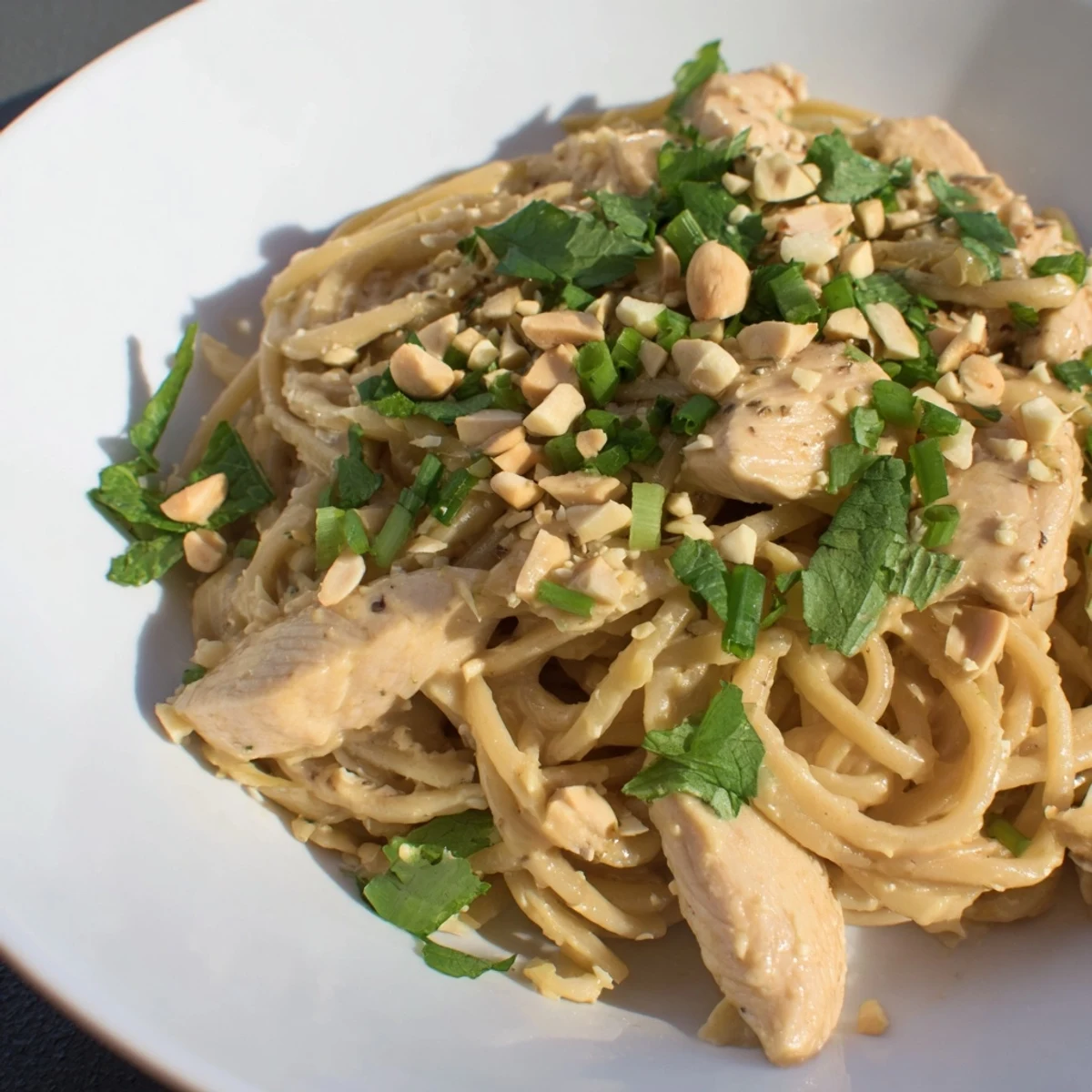 Steaming bowl of Thai Peanut Chicken Pasta, aromatic with fresh herbs and a nutty sauce.