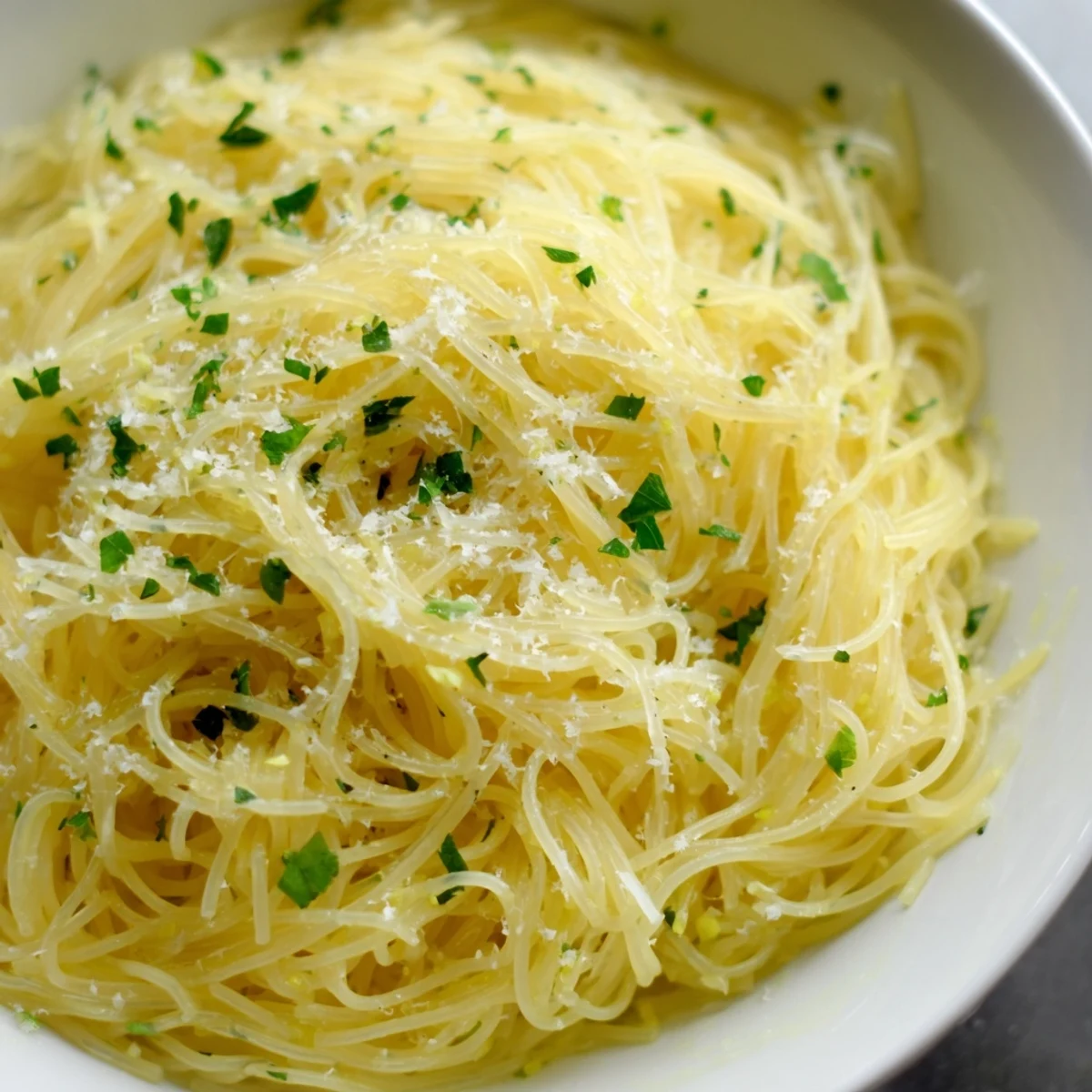Steam rises from a vibrant bowl of Lemon Butter Pasta Light, highlighting melted butter, lemon zest, and grated Parmesan ready to serve.  