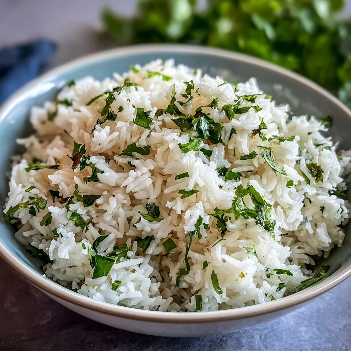 A fluffy bowl of Cilantro Lime Rice, garnished with fresh chopped cilantro and a wedge of lime beside it.