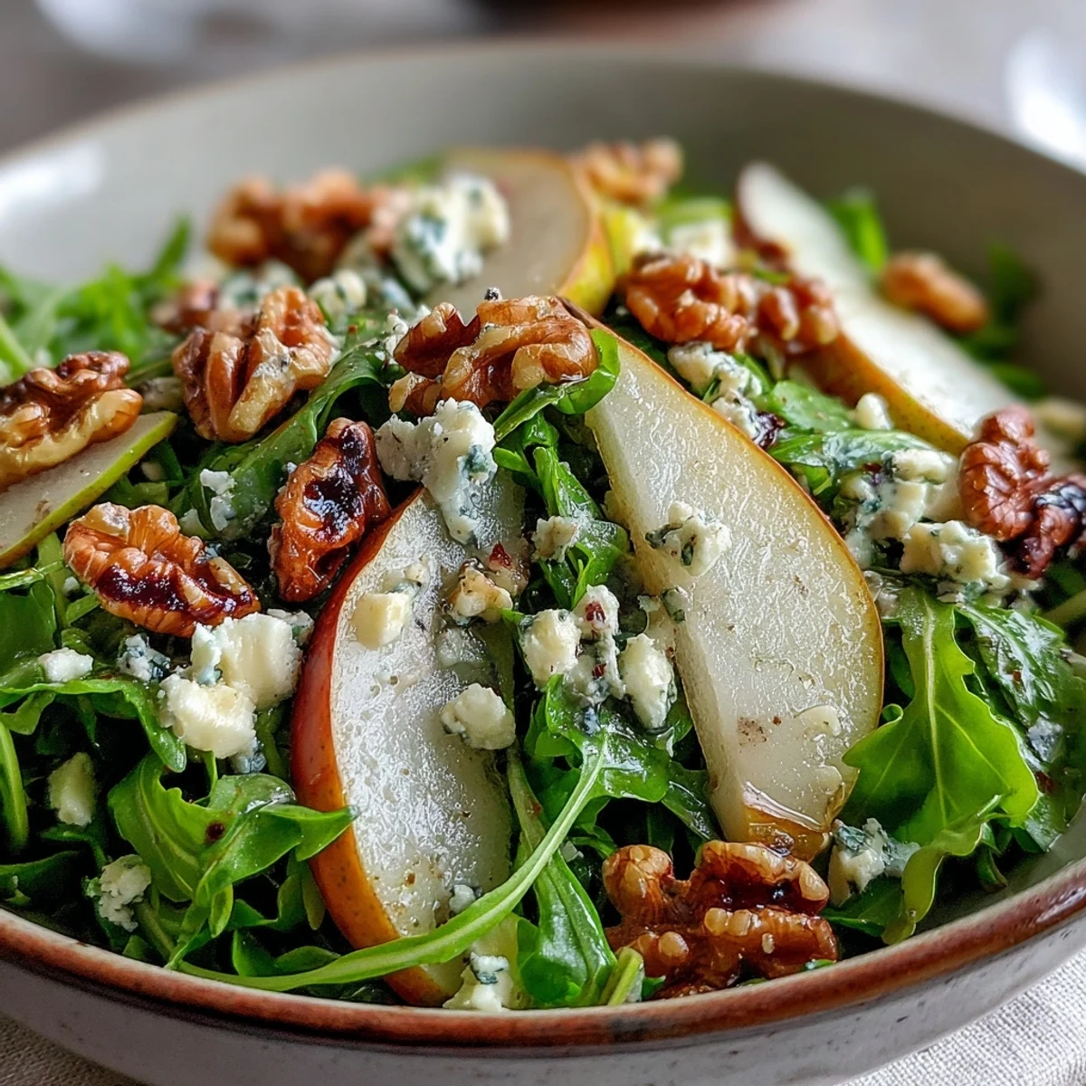Fresh arugula and sliced pears topped with crumbled blue cheese and toasted walnuts for an Arugula and Pear Bowl.