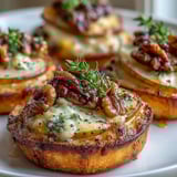 Close-up shot of golden, crisp-edged Pear, Gorgonzola, and Pickled Walnut Pizzettes topped with fresh thyme leaves and arugula.