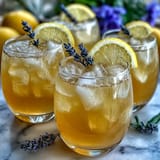 A sparkling lavender lemonade spritz with lemon slices and lavender sprigs in a tall glass.