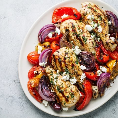 Image of golden Easy Sheet Pan Greek Chicken glistening alongside colorful roasted bell peppers.
