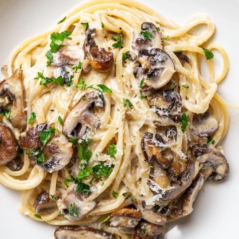A steaming bowl of creamy mushroom linguine, featuring a velvety sauce with garlic and fresh herbs.  
