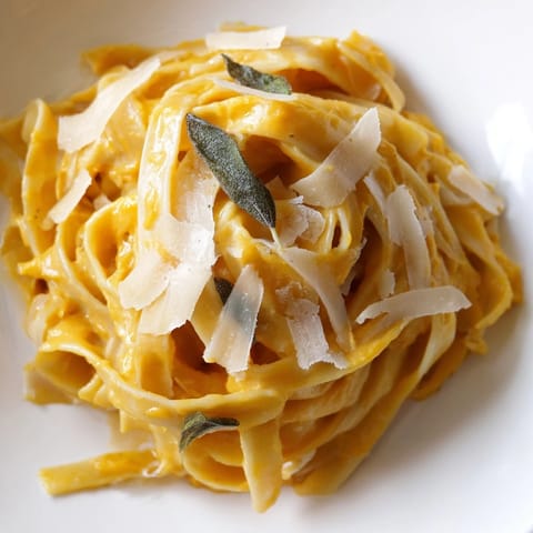 Butternut squash pasta with creamy roasted squash sauce steams in a rustic bowl, ready for dinner.  