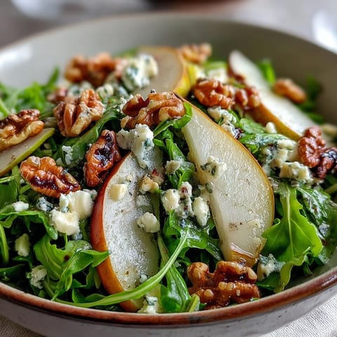 Fresh arugula and sliced pears topped with crumbled blue cheese and toasted walnuts for an Arugula and Pear Bowl.