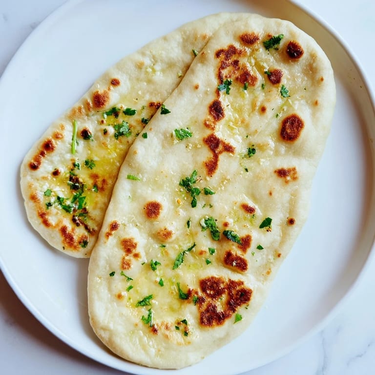 Freshly baked Homemade Garlic Naan Bread, fragrant with garlic, perfect for scooping up delicious curry.