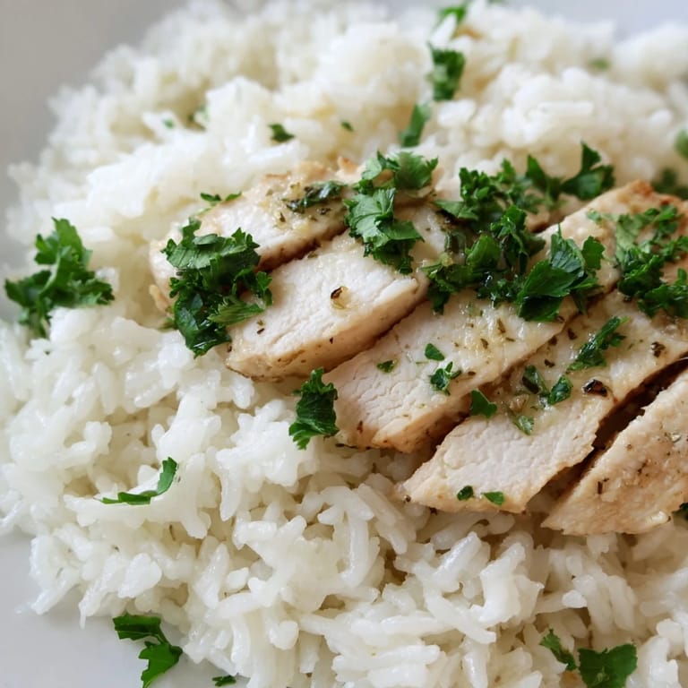 Comforting Garlic Butter Rice with Chicken served in a white bowl, featuring lemon wedges for a bright finishing touch.