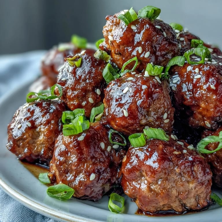 A spoon lifts a saucy Easy Sweet and Sour Crock Pot Meatball over steamed rice, ideal for a weeknight dinner.