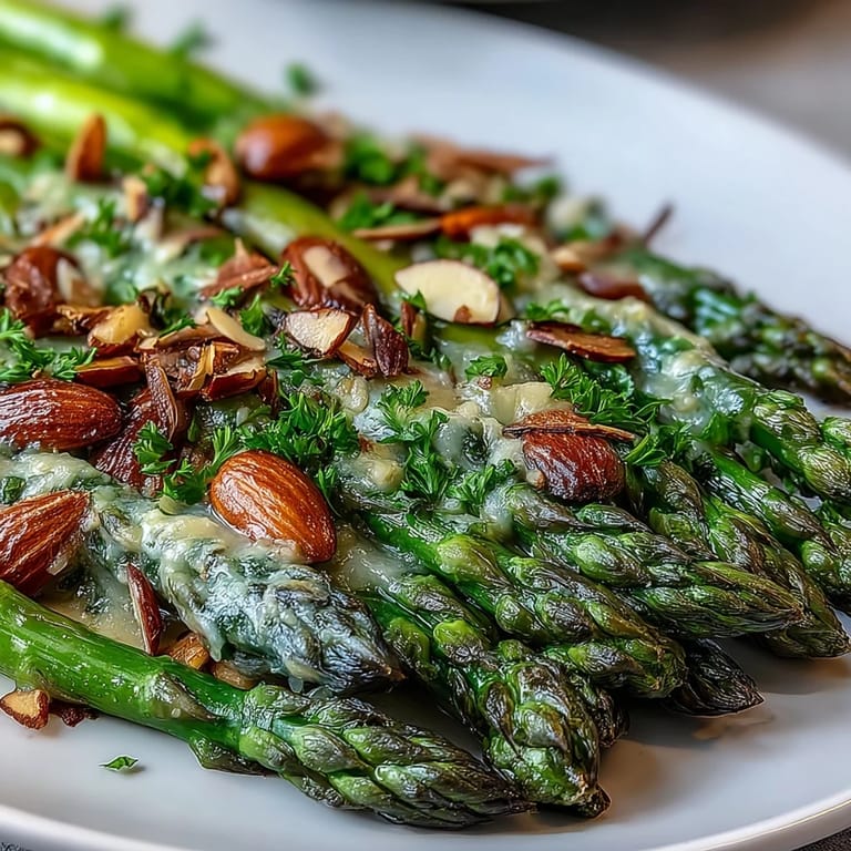 Bright asparagus spears glistening with lemon butter sauce, garnished with crunchy sliced almonds and fresh parsley.