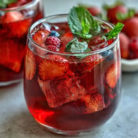 Vibrant iced hibiscus berry tea with fresh fruit, chilled and ready to serve.